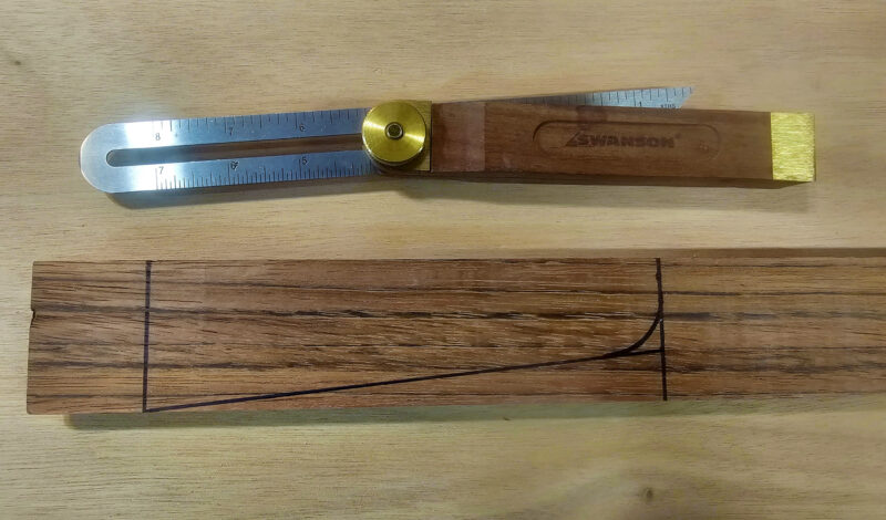 A skeg marked out for cutting and shaping on a block of wood