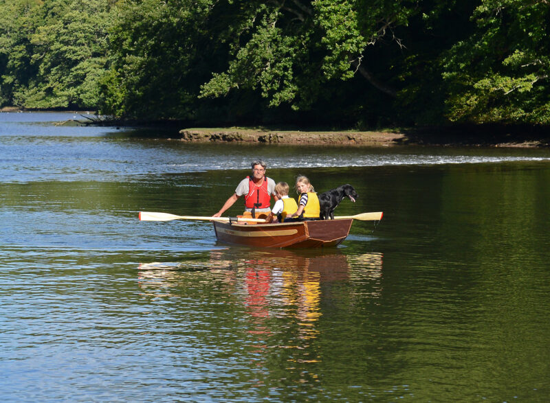 Man with two children and a dog in a Seahopper Lighter under oars.