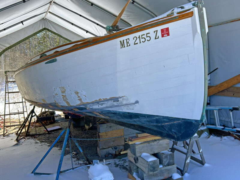 Bow shot of a wooden catboat under boom tent