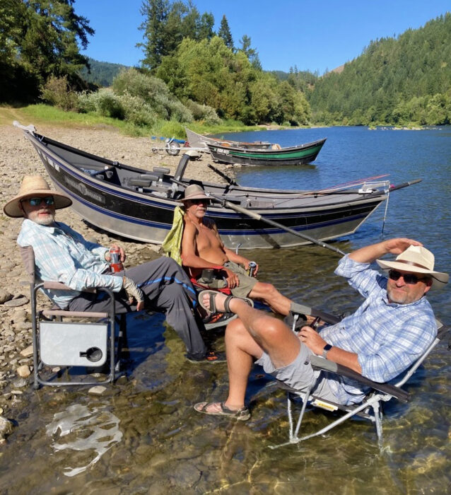 Men with driftboats pulled into rocky shore for lunch break.