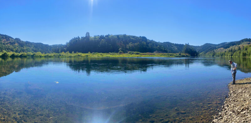 Man on foreshore beside clear still water.