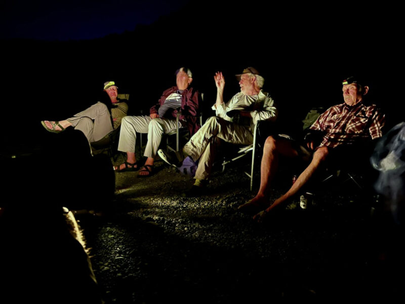 Four men chatting beside a campfire.