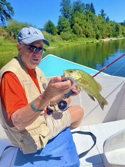 Man looking at a landed smallmouth bass before releasing it.