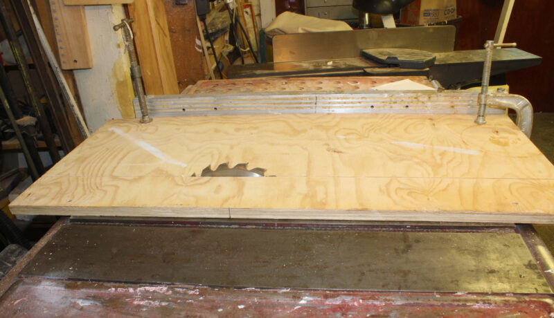 Table saw blade cutting up through plywood base.