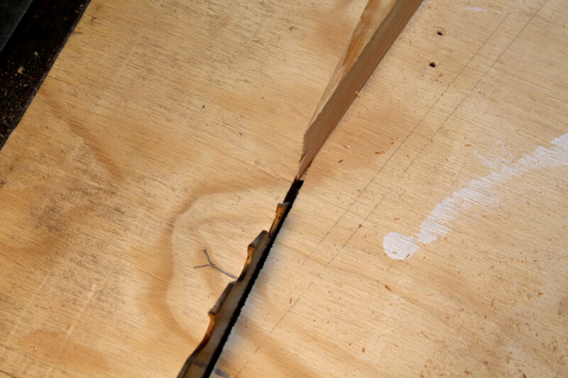 The point of a wedged outfeed close to a table saw blade.