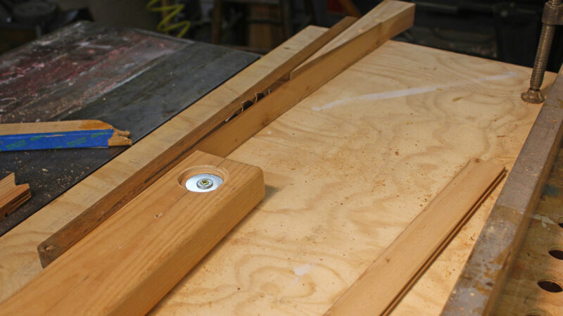 A laminate strip being forced away from the stock by a table saw’s outfeed fence.