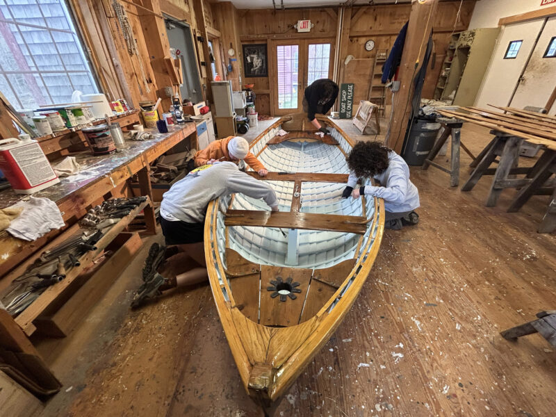 Students work on refinishing a Catspaw Dinghy.