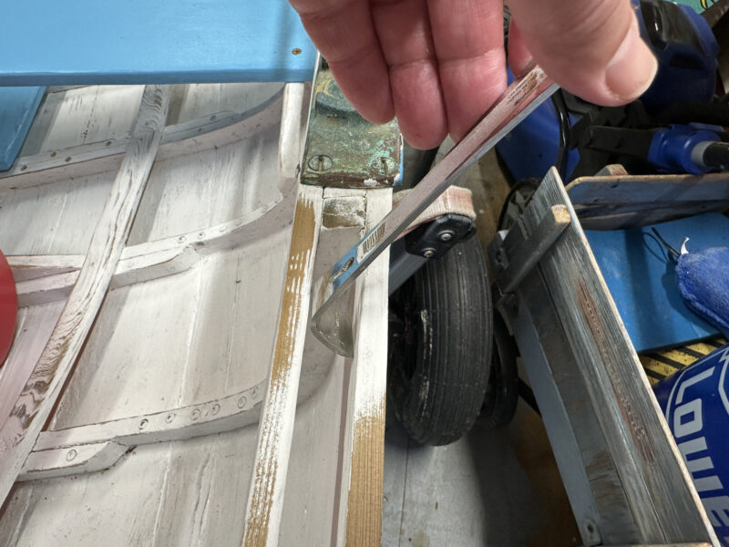 Small pry bar being used as scraper in a gunwale.