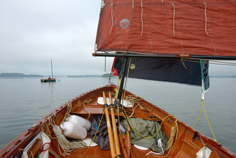 Lines and other gear stowed at the bow of a small wooden sailboat.