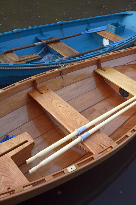 Two skiffs moored alongside one another—one painted, one varnished.