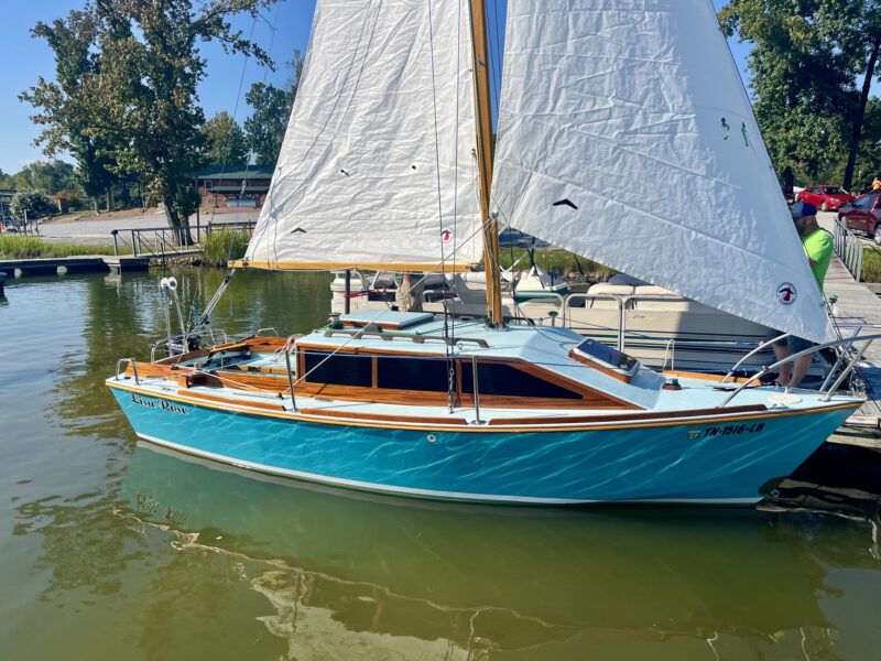Glen-L 19 alongside a dock with sails raised.