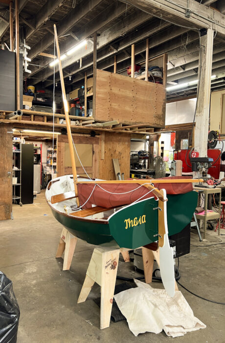 Nutshell Pram with lowered rig on boatstands in workshop.
