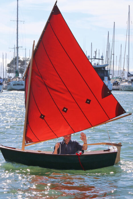 Man sailing Nutshell Pram waving and smiling.