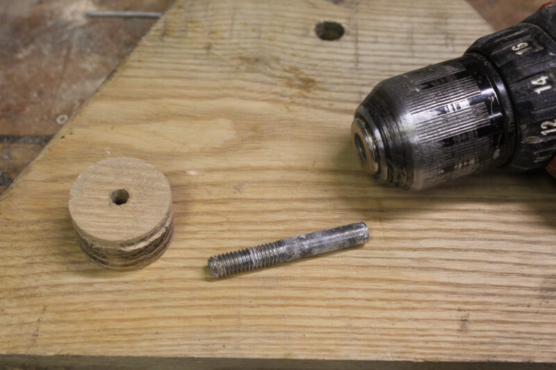 A wooden plug with threaded bolt and power drill.