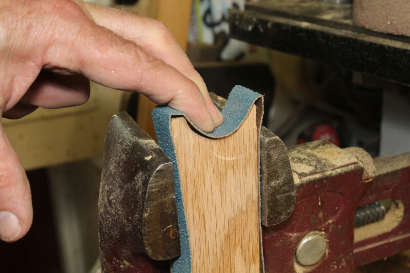 Holding a piece of wood with a sanding belt in a vise.