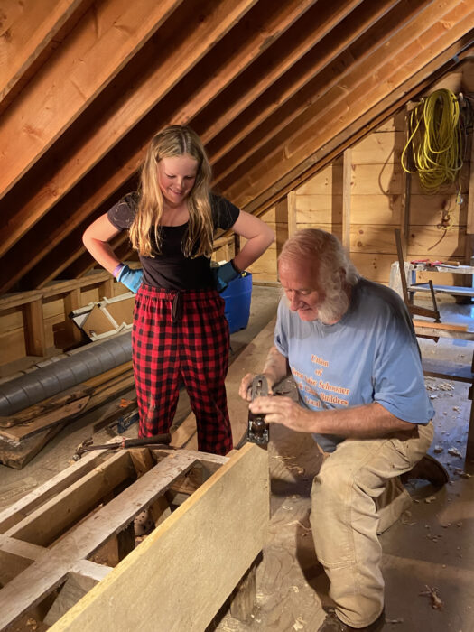 A boatbuilder demonstrates how to use a plane.