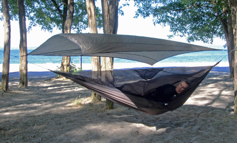 A man settling into a side-entry Hennessy hammock.