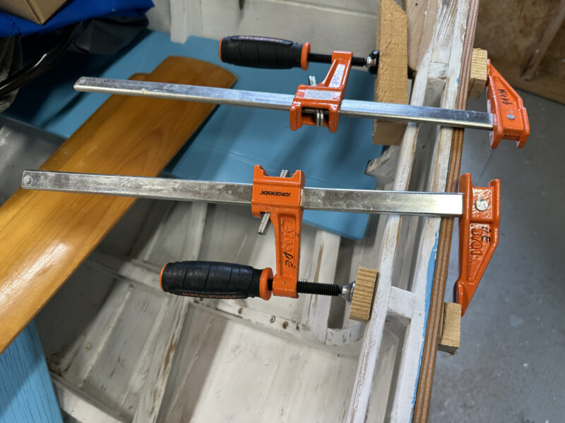 Two steel bar clamps with wooden pads protecting the work being held.