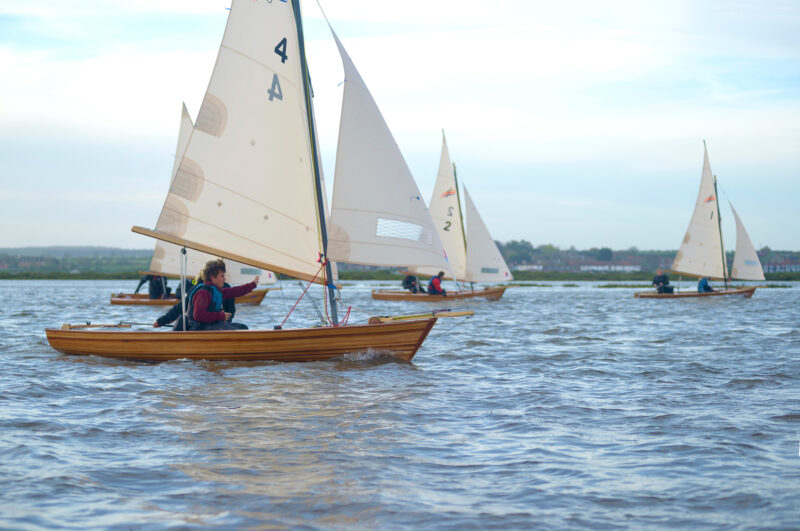 Fleet of Windsong sailing dinghies on downwind course.