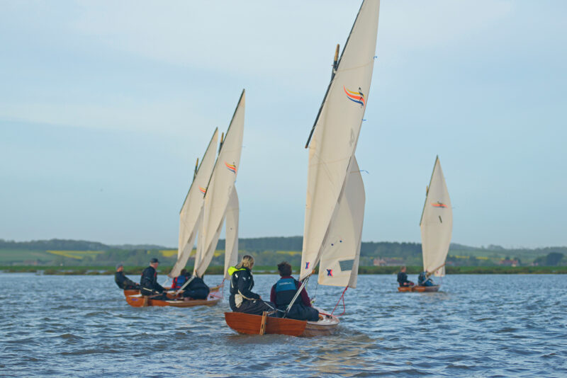 Four Windsong dinghies sailing away on a reach.