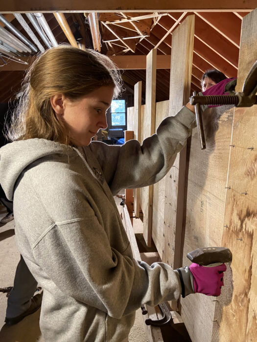 A girl uses a blacksmith hammer as a backing iron.