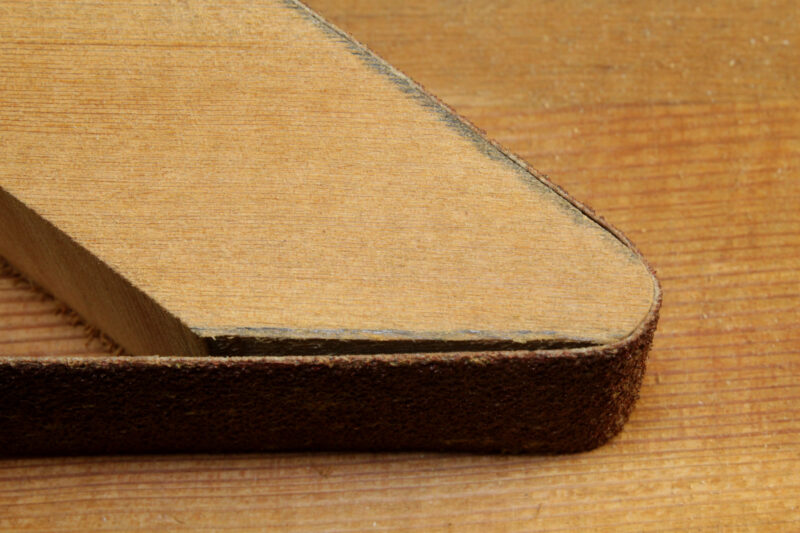 The rounded end of a sanding bow with sanding belt wrapped around it.