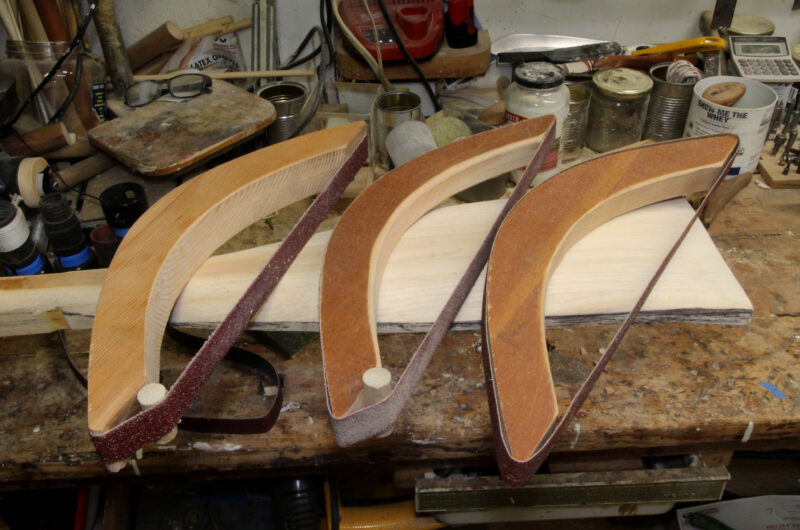 Three sanding bows made of different woods and with different-grit sanding belts.