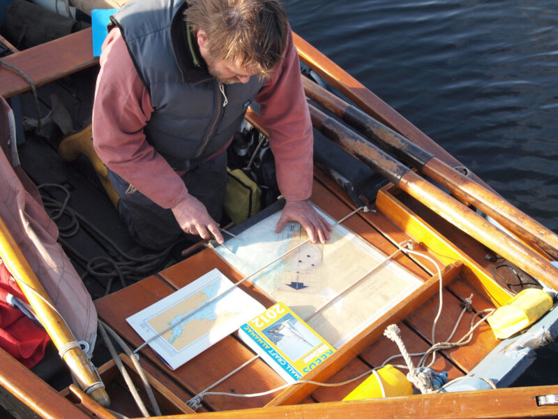 A man in a small open boat consults his chart.